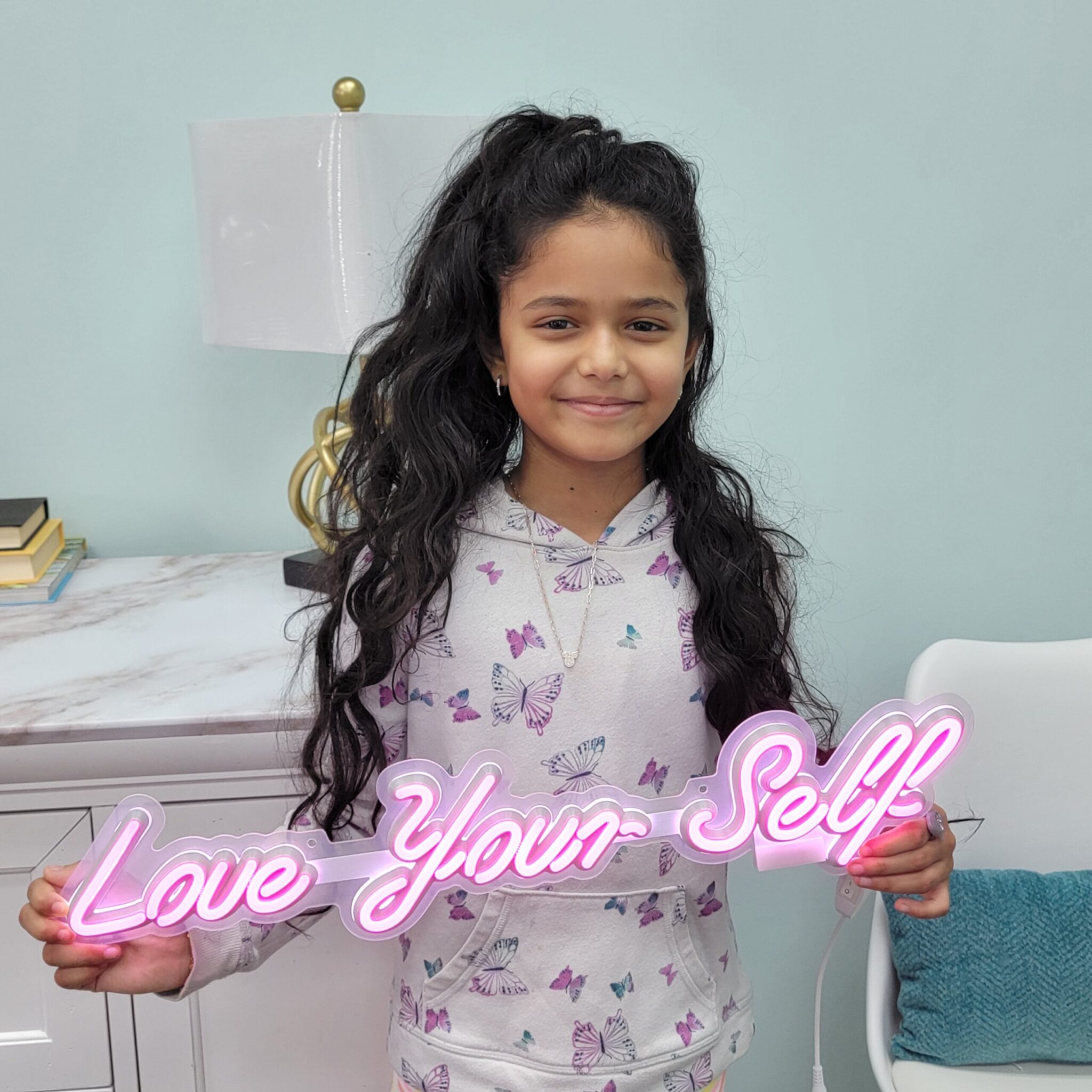 Pretty Girl smiling holding Love-Your-Self Neon Sign at 904 Dental Care